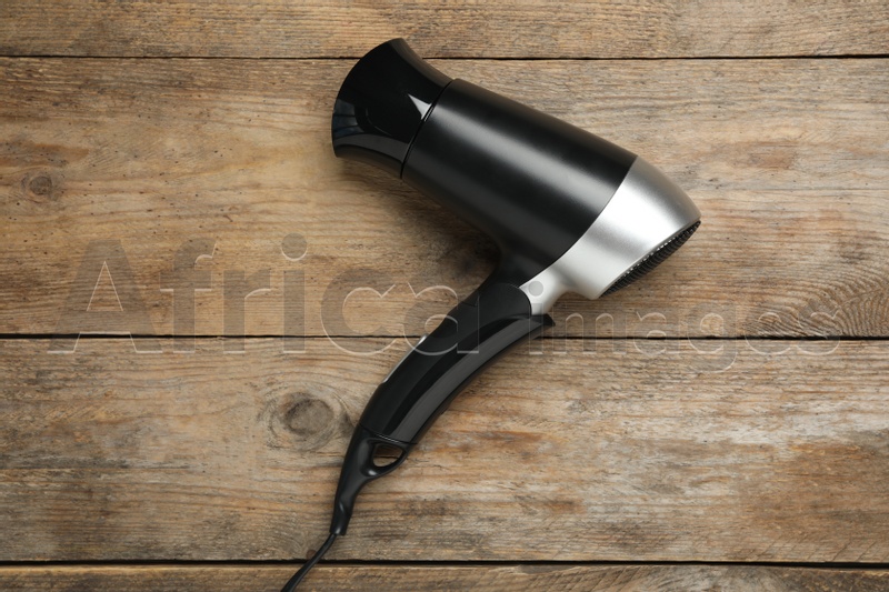 Hair dryer on wooden table, top view. Professional hairdresser tool