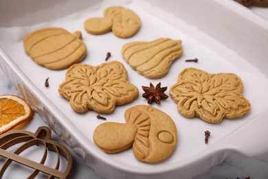 Photo of Different tasty cookies, spices and cutter on white parchment