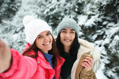 Friends taking selfie outdoors on snowy day. Winter vacation