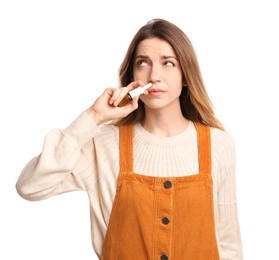 Sick young woman using nasal spray on white background