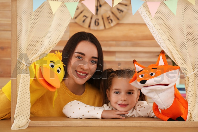 Mother and daughter performing puppet show at home