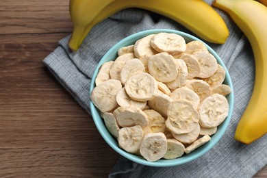 Freeze dried and fresh bananas on wooden table, top view