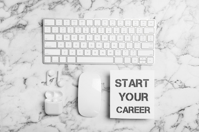 Photo of Flat lay composition with words START YOUR CAREER, computer keyboard, mouse and earphones on white marble table
