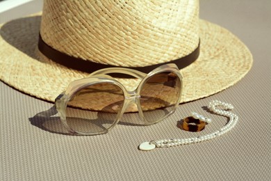 Stylish hat, sunglasses and jewelry on grey surface, closeup