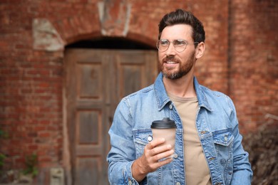 Handsome bearded man with paper cup outdoors. Space for text