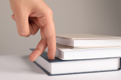 Woman imitating stepping up on books with her fingers against grey background, closeup