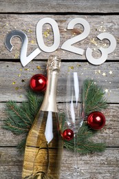 Happy New Year 2023! Flat lay composition with bottle of sparkling wine on wooden table