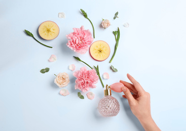 Top view of woman spraying perfume on white background, apple and flowers representing aroma