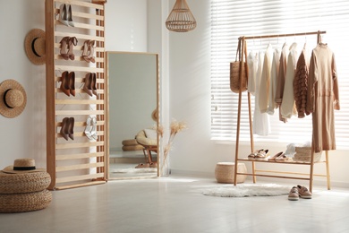 Modern dressing room interior with racks of stylish women's clothes and shoes