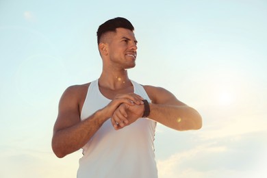 Man with athletic body checking fitness bracelet outdoors