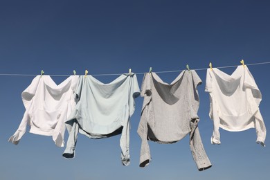 Photo of Washing line with drying clothes and clothespins under blue sky