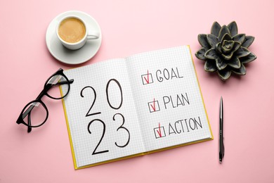 Flat lay composition of notebook with text 2023 Goal, Plan, Action on pink background. New Year aims