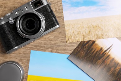 Vintage photo camera and beautiful printed pictures on wooden table, flat lay. Creative hobby