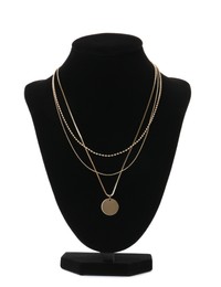 Stylish golden necklace on jewelry bust against white background