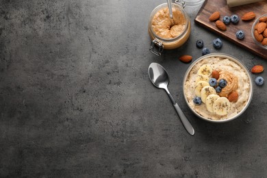 Tasty oatmeal porridge with toppings served on grey table, flat lay. Space for text