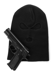 Black knitted balaclava and pistol on white background, top view