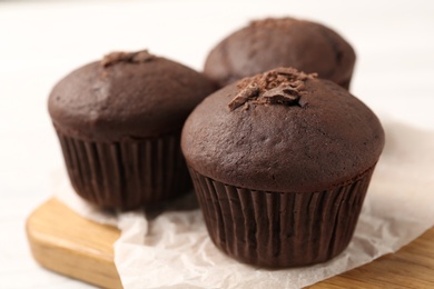 Photo of Delicious cupcakes with chocolate crumbles on wooden board, closeup