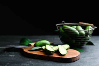 Fresh seedless avocados with green leaves on table against dark background. Space for text