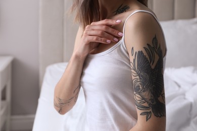 Beautiful woman with tattoos on body at home, closeup