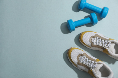 Dumbbells, sneakers and space for text on light grey background, flat lay. Physical fitness