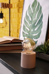 Modern night lamp, houseplants and decor on table indoors