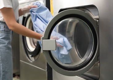 Young woman unloading washing machine in dry-cleaning, closeup