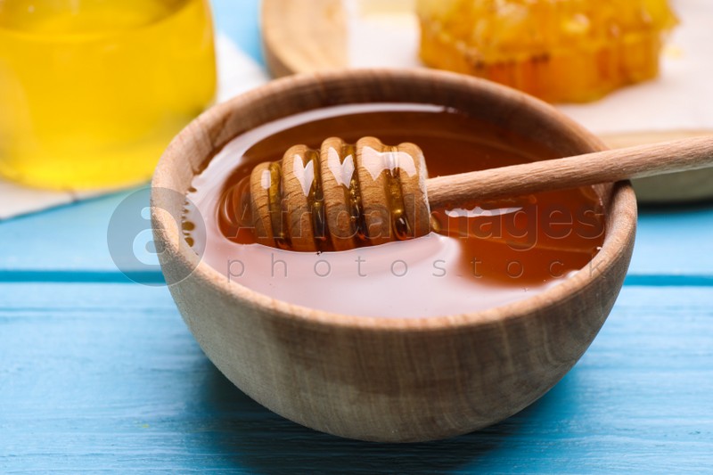 Photo of Tasty aromatic honey on light blue wooden table, closeup