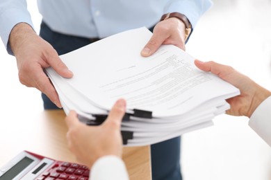 Photo of Man giving documents to colleague in office, closeup