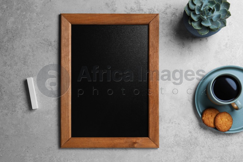 Clean small chalkboard, coffee and cookies on light grey table, flat lay