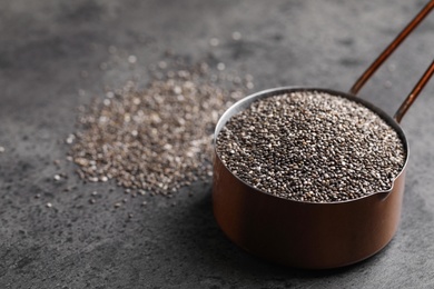 Photo of Saucepan of chia seeds on grey table, space for text
