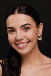 Young woman with elegant pearl earrings on black background