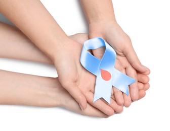 Photo of People holding light blue ribbon with paper blood drop on white background, top view. World Diabetes Day