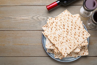 Stack of traditional matzos and red wine on wooden table, flat lay. Space for text