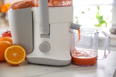 Modern juicer and fresh oranges on table in kitchen, closeup