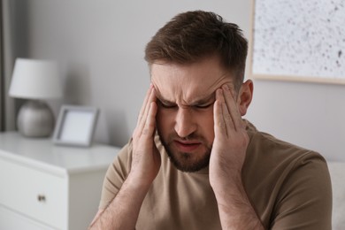 Young man suffering from migraine at home