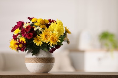 Bouquet of beautiful chrysanthemum flowers on table in room, space for text