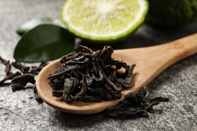 Dry bergamot tea leaves and fresh fruit on grey table, closeup