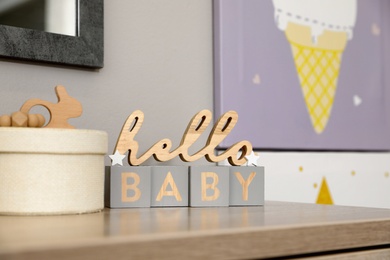 Decorative phrase HELLO BABY on table in baby room. Interior design
