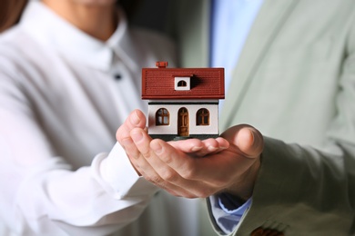 Young couple holding house model, closeup. Home insurance