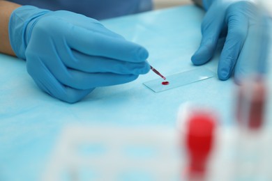 Doctor with blood sample from finger at table, closeup