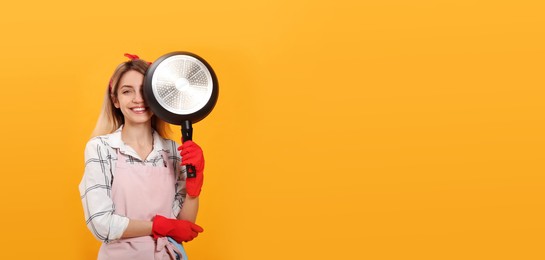 Young housewife with frying pan on yellow background. Space for text
