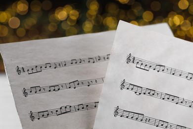 Photo of Closeup view of note sheets against blurred lights. Christmas music