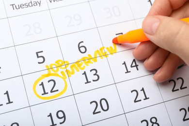 Woman marking date of job interview in calendar, closeup