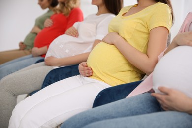 Group of pregnant women at courses for expectant mothers on blurred background, closeup