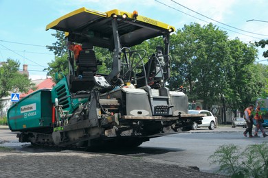 MYKOLAIV, UKRAINE - AUGUST 04, 2021: Workers with road repair machinery laying new asphalt
