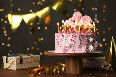 Beautiful birthday cake with burning candles and decor on wooden table. Space for text