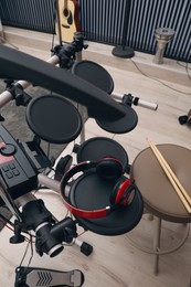Modern electronic drum kit with headphones indoors, closeup. Musical instrument