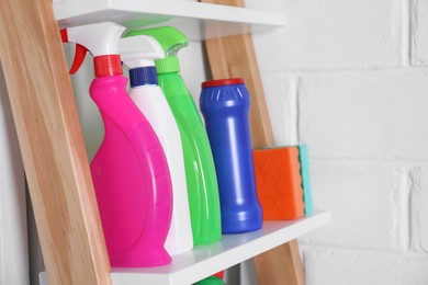 Different detergents and sponges on shelf near white wall indoors