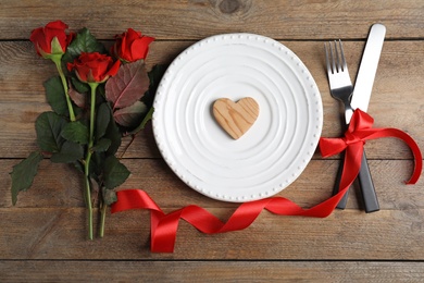 Beautiful place setting for romantic dinner on wooden table, flat lay. Valentine's day celebration