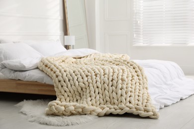 Soft chunky knit blanket on bed in stylish room interior